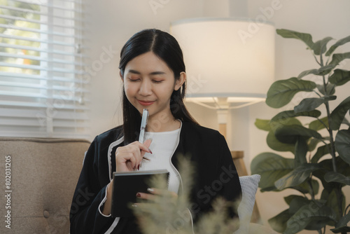 the girl teenaeger is sitting on the cozy couch in the living room of her apartment and spending a free time on what her interasted, sitting happily on the comfrotable sofa photo