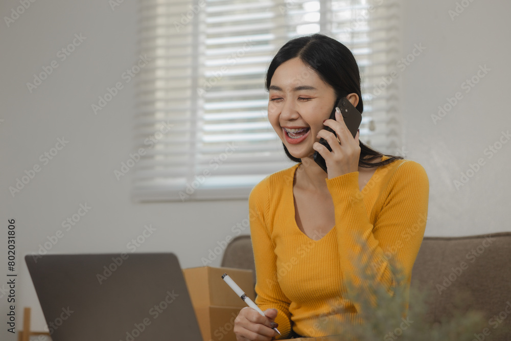 A beautiful female entrepreneur of an online small business is proudly working in her personal warehouse with boxes full of merchandise, Verify customer information before delivering the product A beautiful female entrepreneur of an online small business is proudly working in her personal warehouse with boxes full of merchandise, Verify customer information before delivering the product