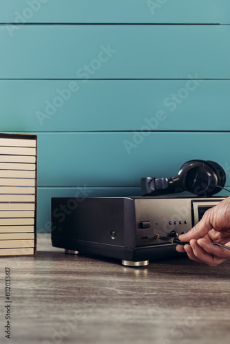 Male hand pressing button on old retro cassette player, closeup photo. Analog technology: Retro cassette deck on wooden background, ideal for vintage music enthusiasts