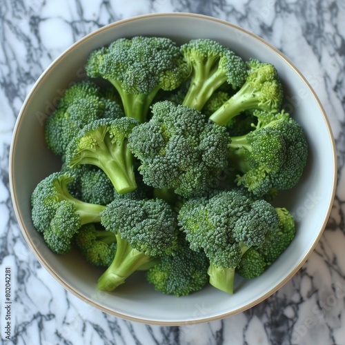 Bowl of fresh green broccoli on marble surface