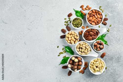 Assortment of nuts in bowls. Cashew, hazelnuts, walnuts, pistachio, pecans, pine nuts, peanut. Food mix background, top view, copy space.