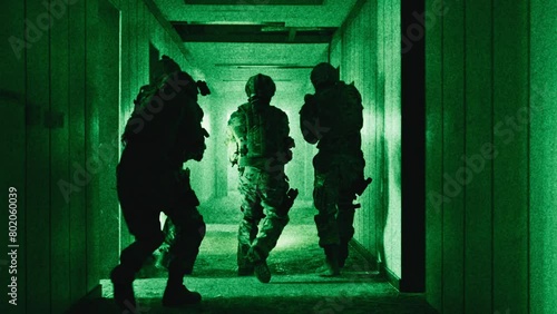 Team of soldiers with guns moving down a corridor night-vision