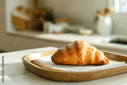 A croissant is sitting on a napkin on a wooden tray