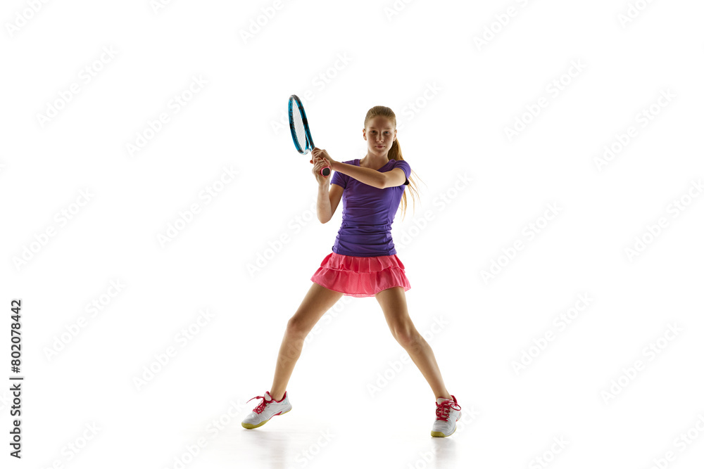 Sporty teenage tennis player in uniform ready to hit two-handed backhand stroke in motion against white studio background. Concept of professional sport, movement, tournament, action. Ad Sporty teenage tennis player in uniform ready to hit two-handed backhand stroke in motion against white studio background. Concept of professional sport, movement, tournament, action. Ad