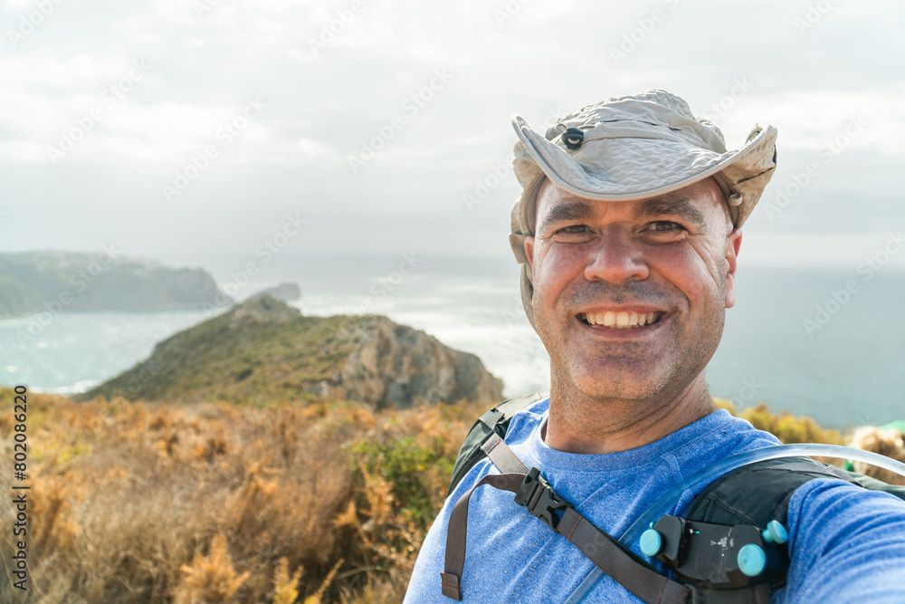 Smiling hiker takes a selfie with amazing landscape with cliffs and sea on background. Smiling hiker takes a selfie with amazing landscape with cliffs and sea on background.