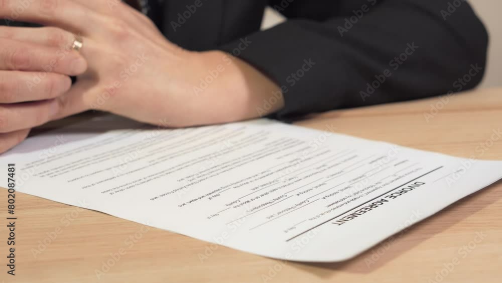 A stressed female reads the divorce agreement and rotates the wedding ring on her ring finger. Concept of marriage problem. A stressed female reads the divorce agreement and rotates the wedding ring on her ring finger. Concept of marriage problem.
