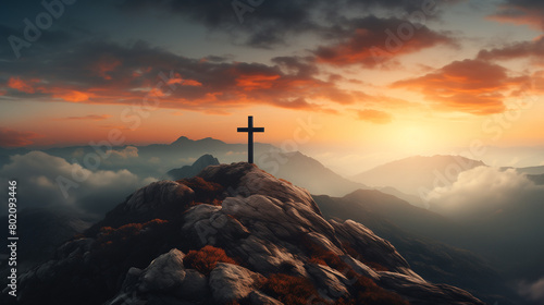 A cross atop the mountain against a beautiful sunset sky, with clouds and mist in the valley below.