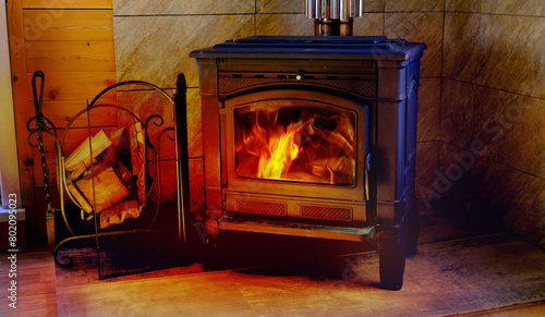 Black metal stove fireplace with wood in a woodpile, cottage, village house. Heating house with firewood. Saving energy on heating. Furnace