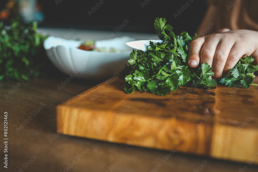 Child is using a cutting board to chop vegetables for a dish Child is using a cutting board to chop vegetables for a dish