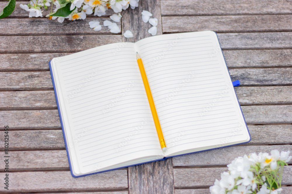 Naklejka premium open notebook with blank pages on wooden table in garden