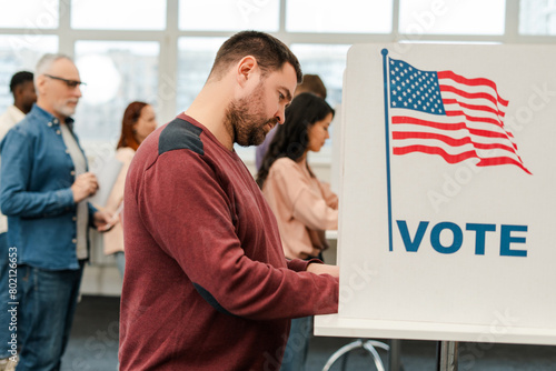 Fotografía Attractive, middle aged man standing in voting booth with American flag, voting