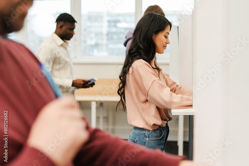 Fotografía Smiling, beautiful, Asian young woman standing in voting booth with American fla