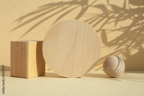 Wooden scenes of different geometric shapes with a shadow of tropical palm leaves on a beige background. Premium podium for advertising your product. Showcase, display case.