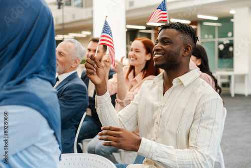 Group of positive, multinational people, US citizens holding American flag, applauding, meeting photo