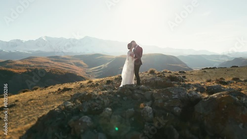 Newlyweds. Married couple in the mountains. A man and a woman in wedding dresses against a background of snow-capped mountains. Wedding couple. A happy family.  photo