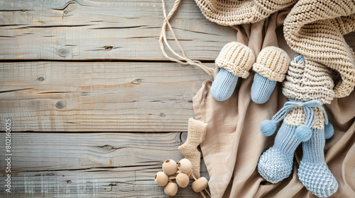 Baby clothes booties and toy on wooden background