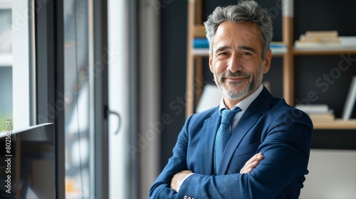 Happy middle aged business man ceo standing in office arms crossed. Smiling mature confident professional executive manager, proud lawyer, confident businessman leader wearing blue suit, portrait