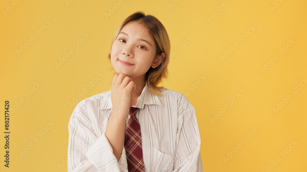 Young woman dressed in shirt and tie, thinks something isolated on yellow background in studio
