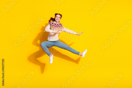 Photo portrait of attractive young woman jumping kick karate dressed stylish knitted warm outfit isolated on yellow color background