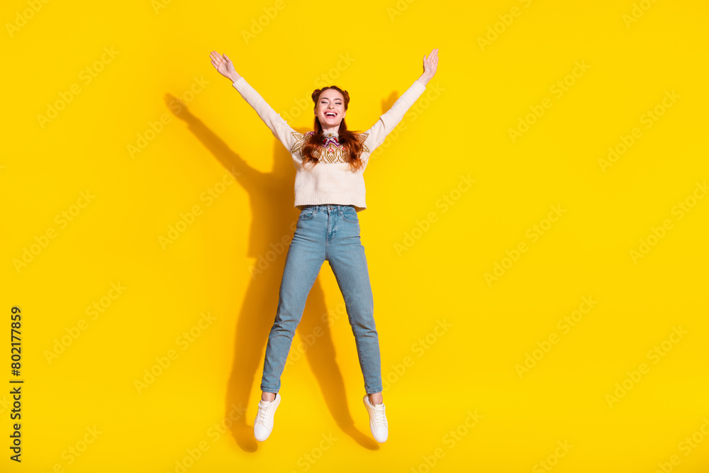 Photo portrait of attractive woman jump raise hands excited dressed stylish knitted warm outfit isolated on yellow color background Photo portrait of attractive woman jump raise hands excited dressed stylish knitted warm outfit isolated on yellow color background