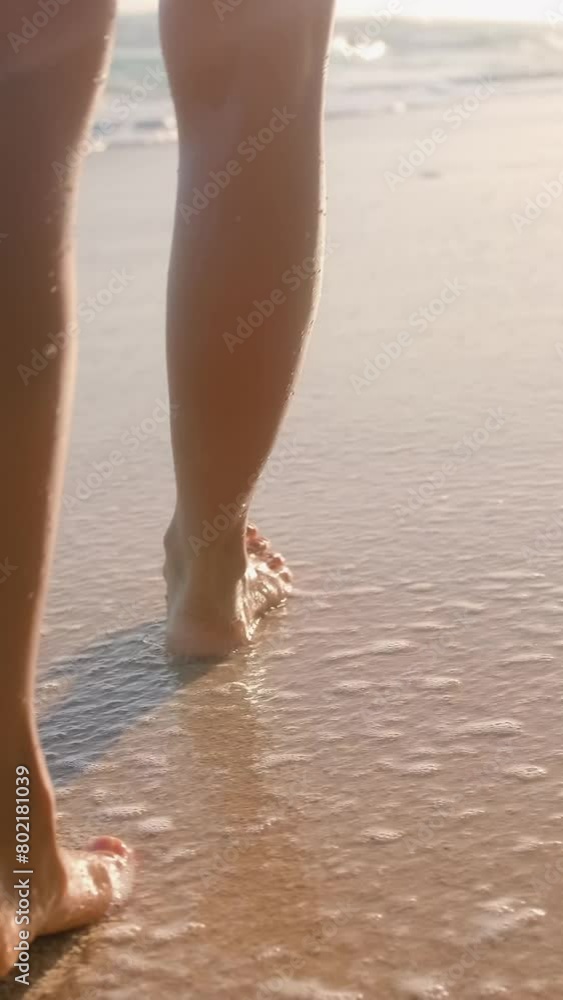 Legs of woman walking along sandy beach washed by foamy waves on southern island with warm sea for swimming and getting beautiful tan or relaxing from bustle of city away from people. Legs of woman walking along sandy beach washed by foamy waves on southern island with warm sea for swimming and getting beautiful tan or relaxing from bustle of city away from people.
