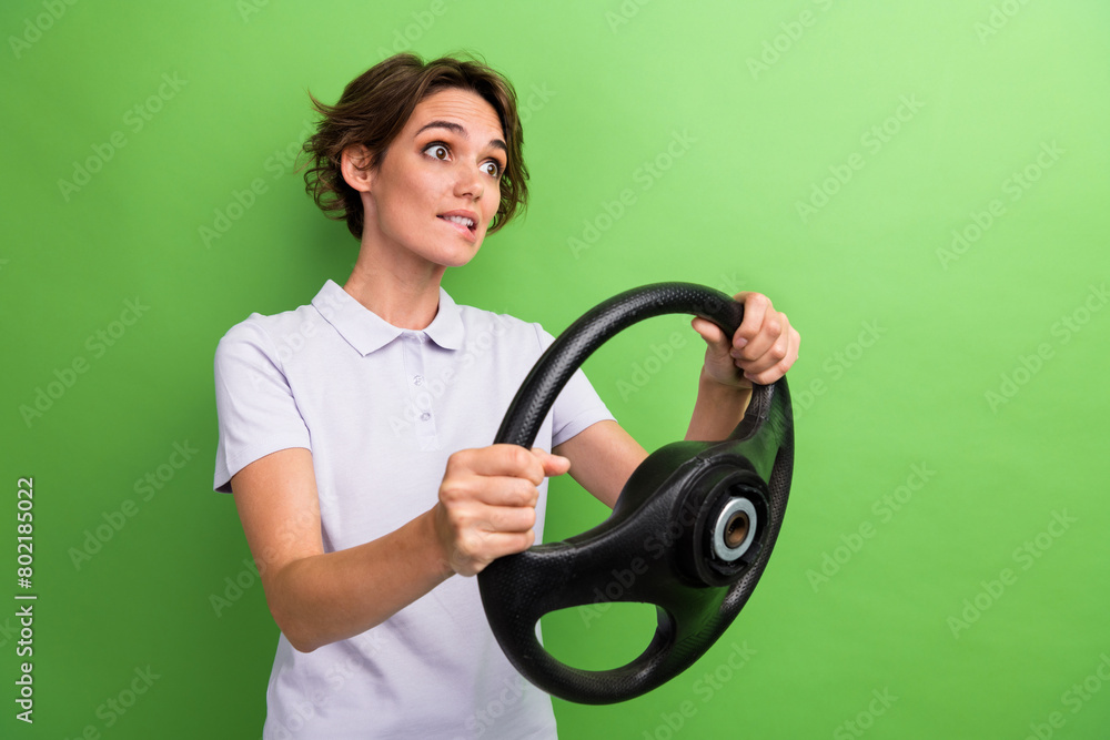 Photo of young lady hold steering wheel automobile bite lips scared passing examination drivers license isolated on green color background Photo of young lady hold steering wheel automobile bite lips scared passing examination drivers license isolated on green color background