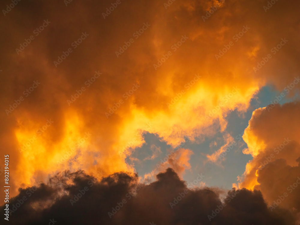 Several cumulus clouds obscuring most of blue sky during golden hour on an evening early in June, southwest Florida, for motifs of transition and disappearance