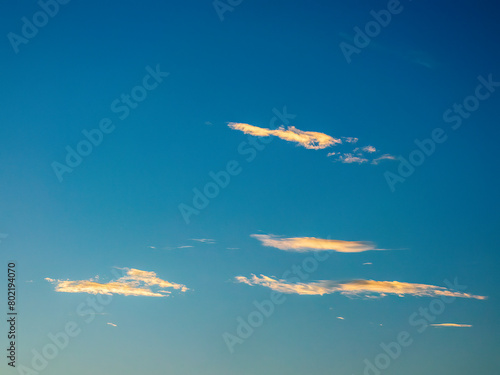 Minimalist cloudscape with slight longitudinal cloudlets drifting in hazy blue sky at sunset in summer, southwest Florida. For motifs of beginnings and endings. photo