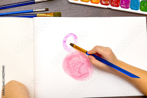 An artist is using a blue brush to paint a pink circle
