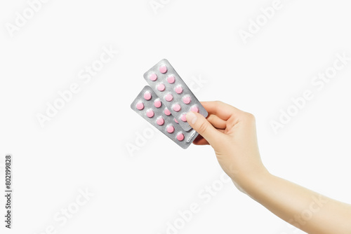 hand holding two blisters with pink pills on a white background