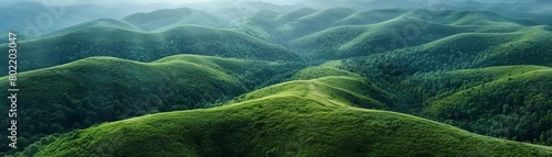 The photo shows a beautiful landscape of rolling green hills. The hills are covered in lush green grass and there are trees in the distance.