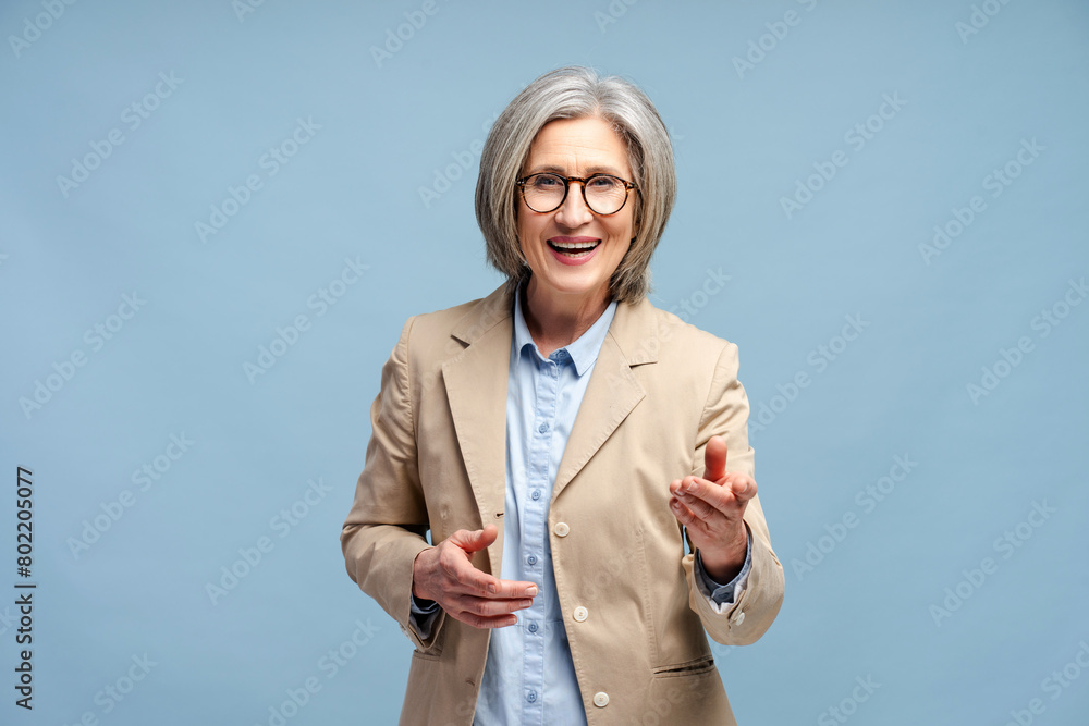 Smiling senior 60 years old woman wearing eyeglasses and stylish suit pointing fingers isolated Smiling senior 60 years old woman wearing eyeglasses and stylish suit pointing fingers isolated