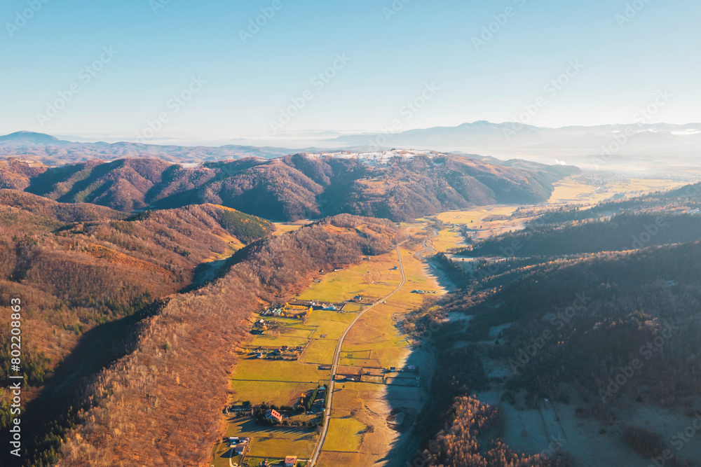 Fototapeta premium A breathtaking aerial view of a lush valley nestled among majestic mountains, creating a picturesque natural landscape