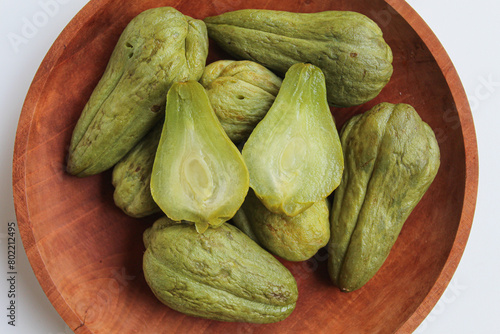 Steamed fruit of small Chayote or Sicyos edule, on wooden plate, isolated on white background, flat lay or top view photo