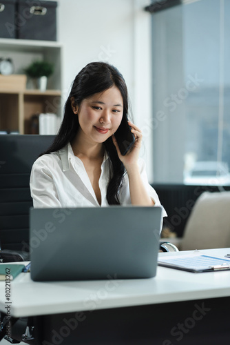 Businessman using laptop computer and smartphone  in office. Happy woman, entrepreneur, small business owner working online. © NINENII