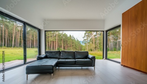 Minimalist interior design of modern living room  home. Black leather sofa in spacious room in villa in forest.