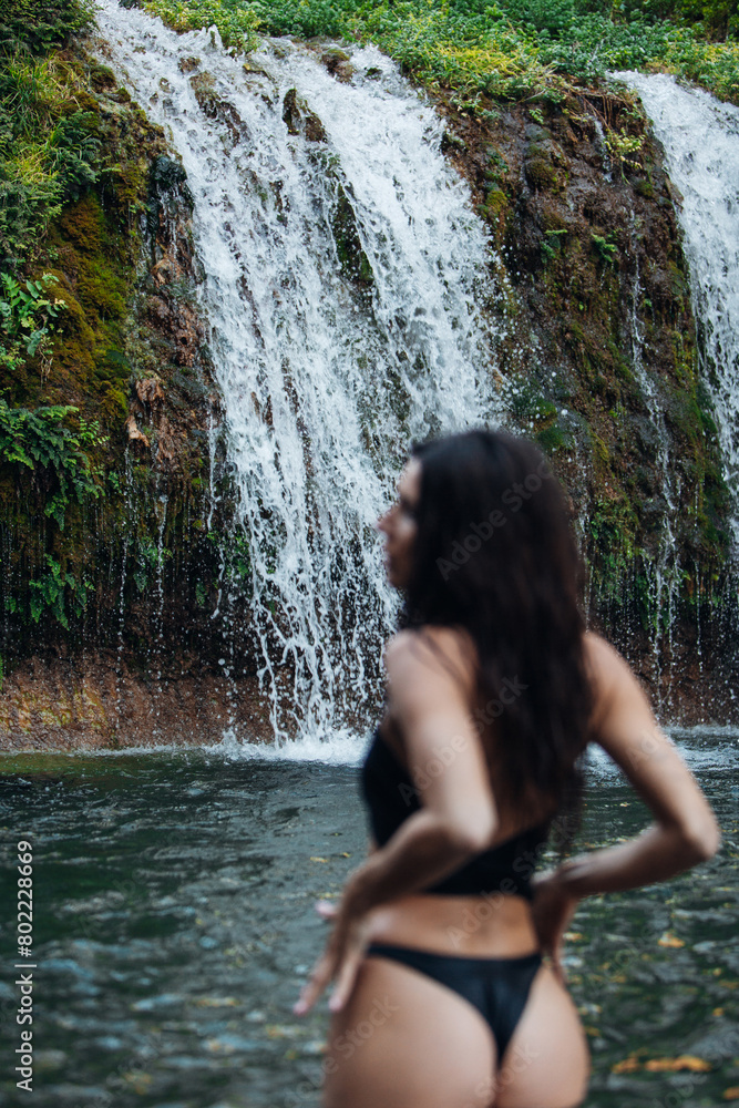 Women in bikini stand in front of a waterfall in Bali Women in bikini stand in front of a waterfall in Bali