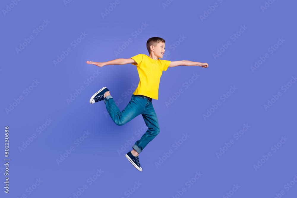 Full length photo of cheerful positive boy wear trendy yellow clothes have fun flight fly air isolated on violet color background Full length photo of cheerful positive boy wear trendy yellow clothes have fun flight fly air isolated on violet color background