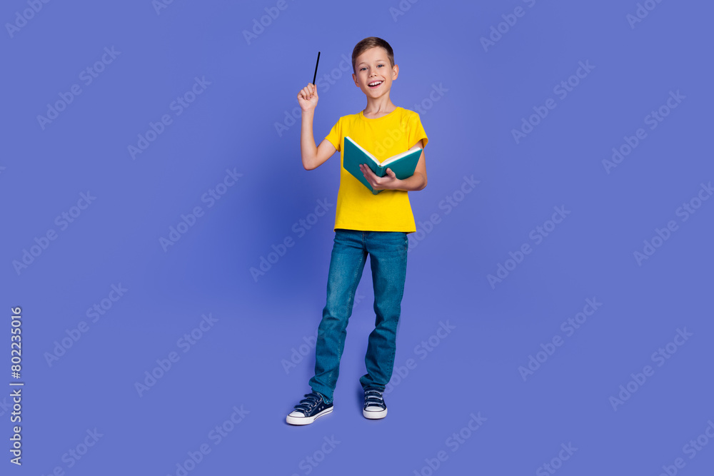 Photo of clever cute boy nerd bookworm wear stylish yellow clothes hold book finger up nice solution isolated on purple color background Photo of clever cute boy nerd bookworm wear stylish yellow clothes hold book finger up nice solution isolated on purple color background