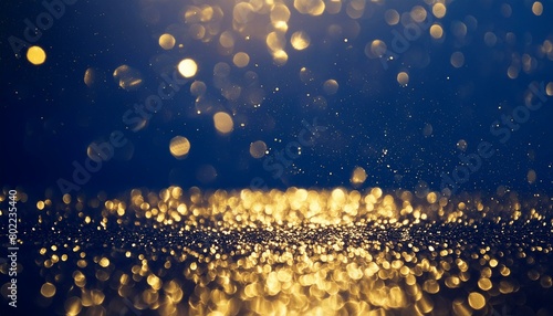 An abstract background featuring dark blue and golden particles. Christmas golden light shines, creating a bokeh effect on the navy blue background. Gold foil texture is also present photo