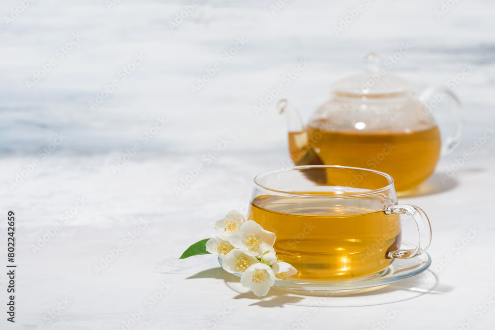 glass cup and teapot with jasmine green tea on a white background glass cup and teapot with jasmine green tea on a white background