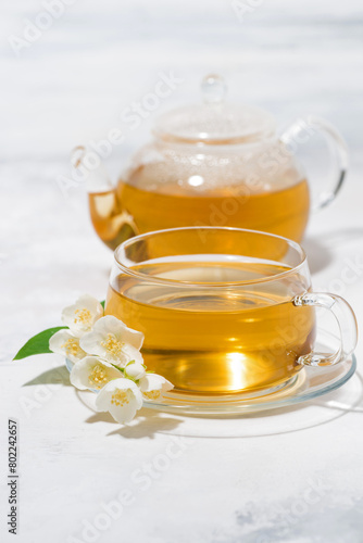 glass cup and teapot with jasmine green tea on a white table