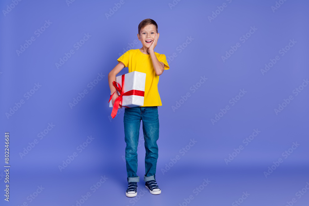 Photo of positive cheerful boy wear stylish yellow clothes receive unexpected big gift holiday event isolated on violet color background Photo of positive cheerful boy wear stylish yellow clothes receive unexpected big gift holiday event isolated on violet color background