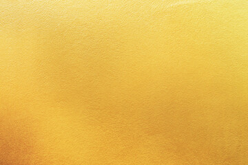 Gold wall texture background. Yellow shiny gold foil paint on wall surface with light reflection