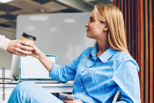 Cropped image of male colleagues giving coffee cup to female coworker having friendly atmosphere in office,woman getting nug with beverage during work break enjoying collaborating with good partner photo