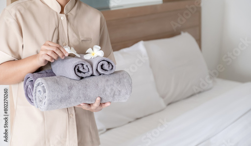 Hands of hotel maid putting plumeria flower and towels on the bed in the luxury hotel room ready for tourist travel photo