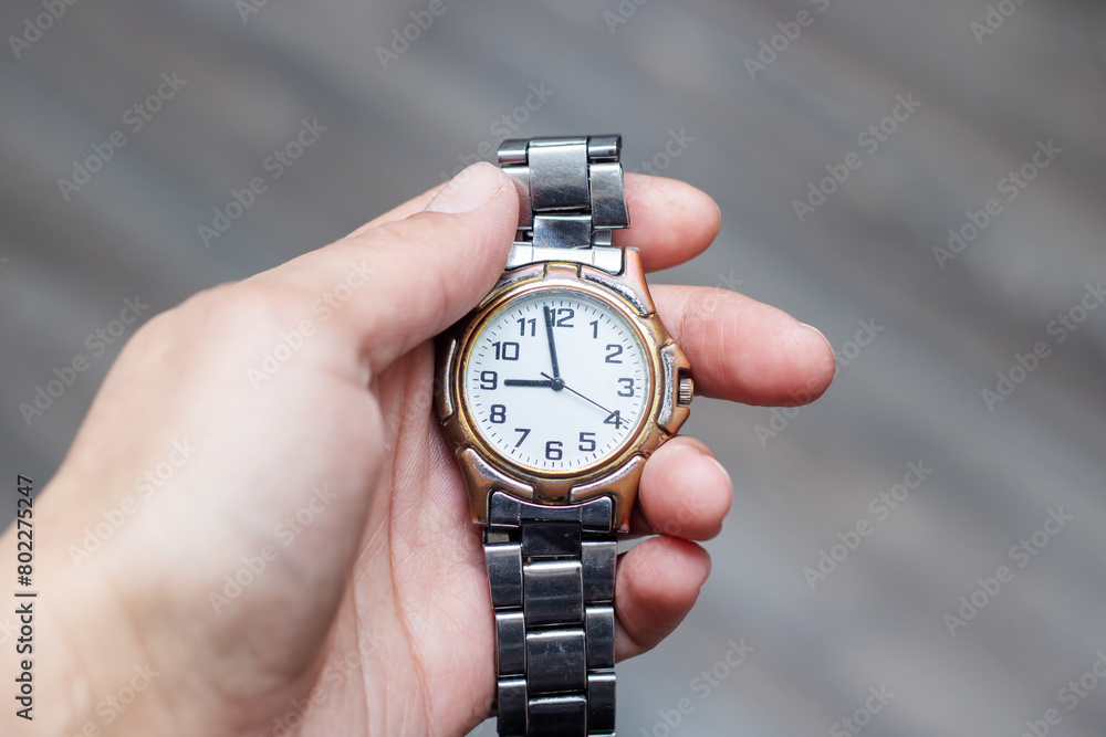 a person is holding a watch in their hand that shows the time a person is holding a watch in their hand that shows the time
