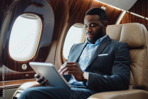 African american businessman in suit using tablet in airplane during business trip. Shallow depth of field © Mikhail