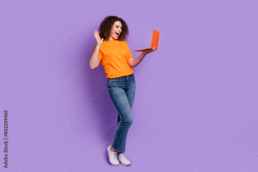 Full length photo of positive adorable woman manager wear trendy clothes speak online wave arm say hi isolated on purple color background Full length photo of positive adorable woman manager wear trendy clothes speak online wave arm say hi isolated on purple color background