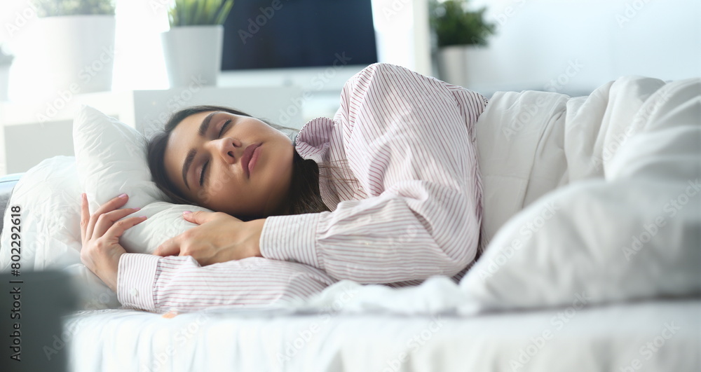Beautiful indian woman peacefully lying in bed sleeping early morning while alarm clock going to ring awakening. Early wake up, not getting enough sleep, oversleep, getting work time concept